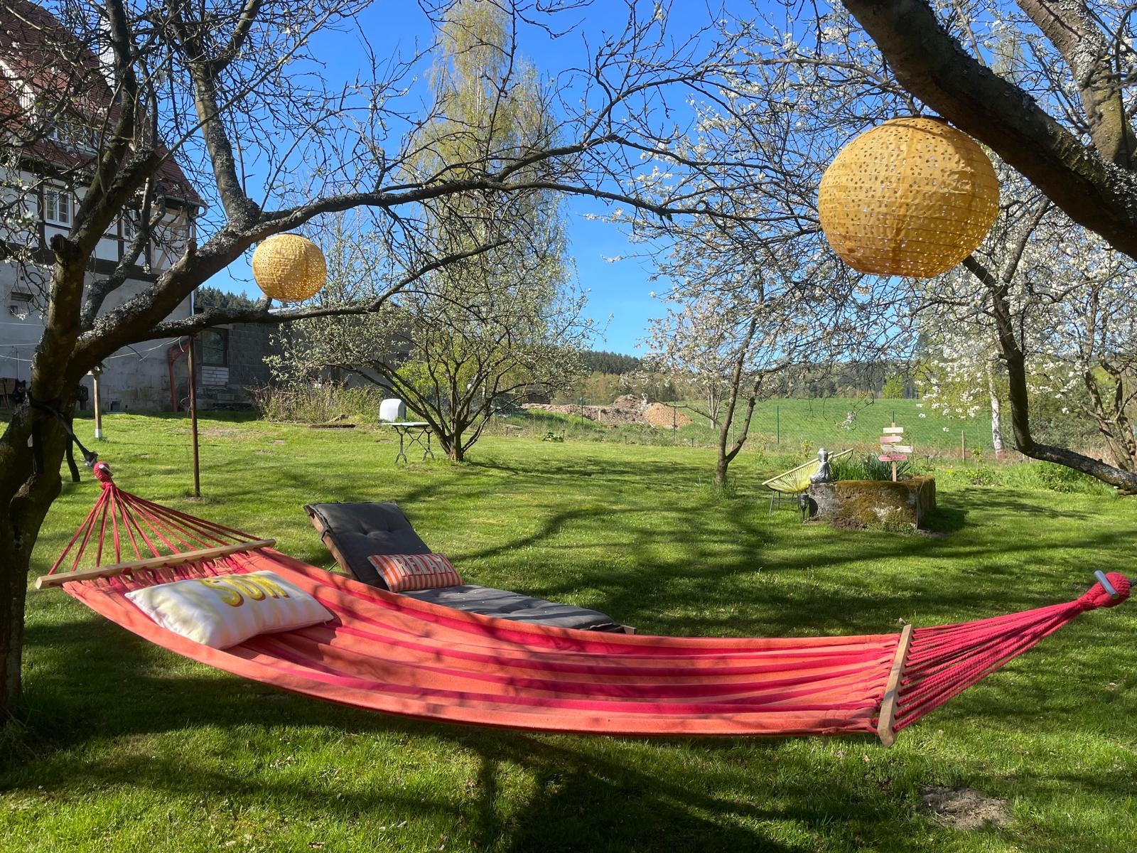 Hängematte unter blühenden Obstbäumen im Garten des Gizobel